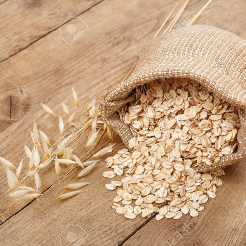 83821101-still-life-oatmeal-in-bag-and-oat-ear-on-wooden-table-uncooked-rolled-oat-flakes