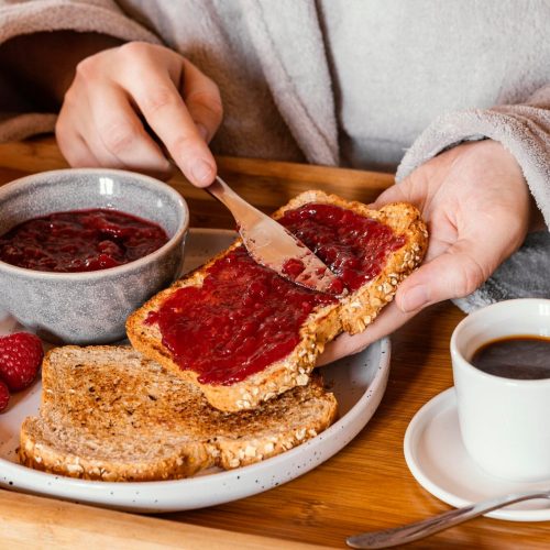 mano-de-primer-plano-poniendo-mermelada-en-pan